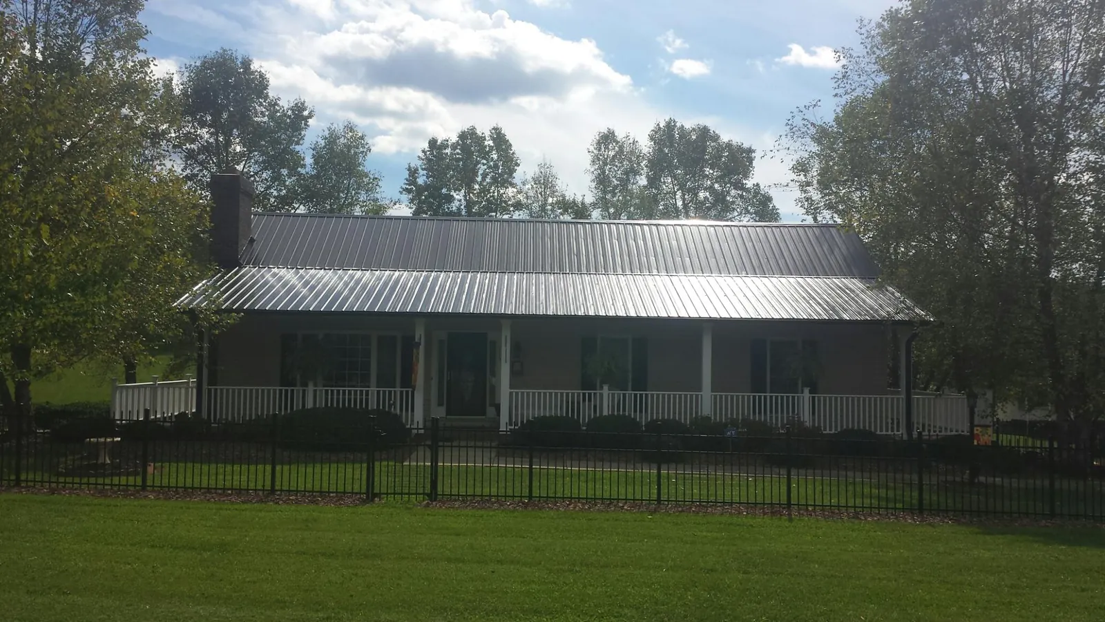 Gray metal roof on a brick ranch with a full width front porch — Gutter Guard Installation work by our crew in Buxton
