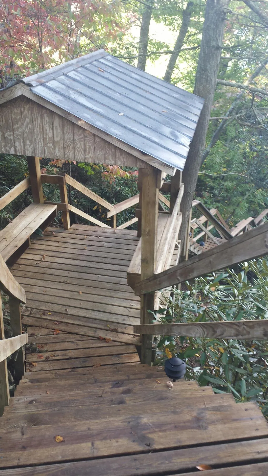 Metal roofed shelter over wooden steps on a wooded walkway — Skylight Repair & Installation work by our crew in Buxton